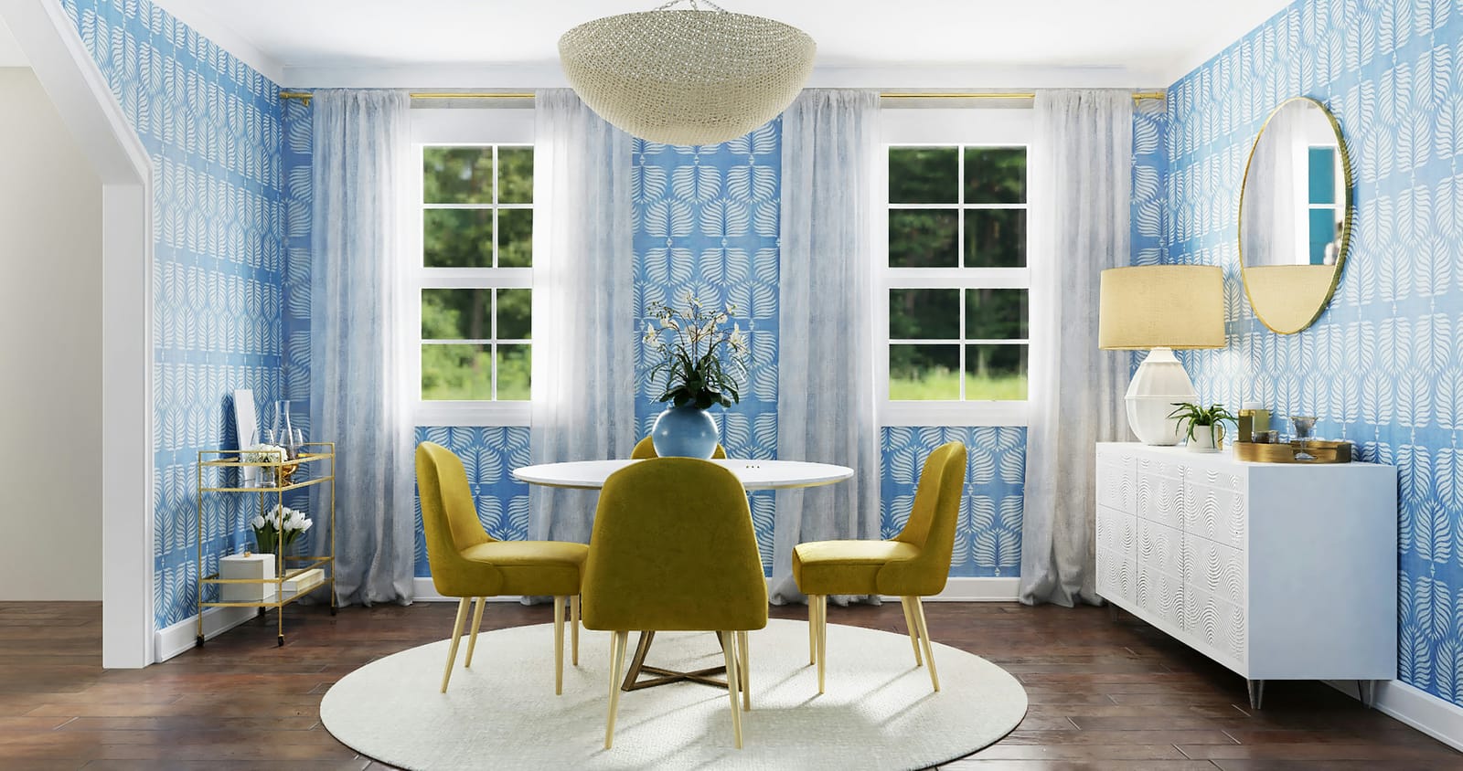 A bright dining room with blue palm-leaf wallpaper, mustard-yellow velvet chairs, a white round table with orchids, and a beaded dome chandelier
