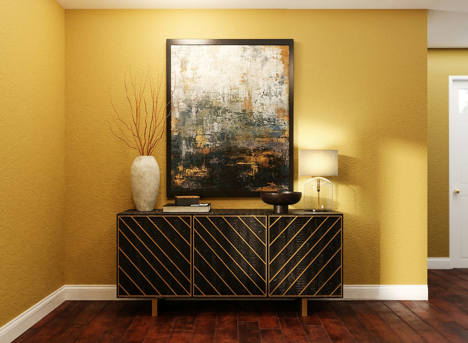 A golden-yellow entryway wall with a black-and-gold chevron sideboard, a large moody abstract painting, coral branches in a stone vase, and a glass table lamp