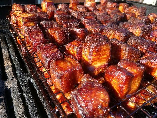 Caramelized, glazed burnt ends lined up on a grill grate